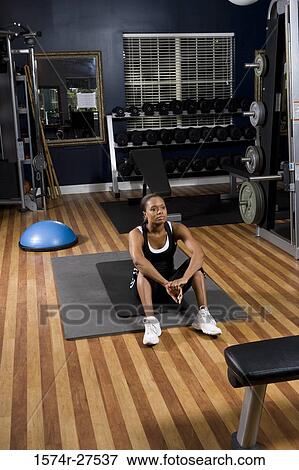 Contemplative young woman sitting on a mat in the gym View Large Photo Image Stock Photo - Contemplative young woman sitting on a mat in the gym. Fotosearch