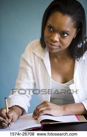 Stock Photo - Contemplative young woman writing in a book. Fotosearch