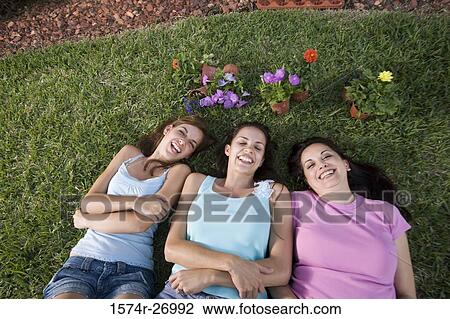 Elevated view of a mother lying with daughters on grass in garden View Large Photo Image Stock Image - Elevated view of a mother lying with daughters on grass in garden. Fotosearch