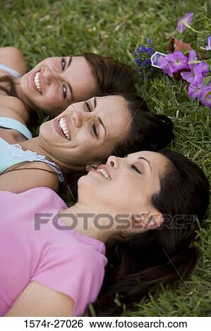 Elevated view of a mother lying with her daughters on grass in garden View Large Photo Image Stock Photograph - Elevated view of a mother lying with her daughters on grass in garden. Fotosearch