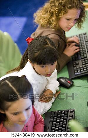 Stock Photo - Elevated view of schoolgirls with computer keyboards in the library. Fotosearch