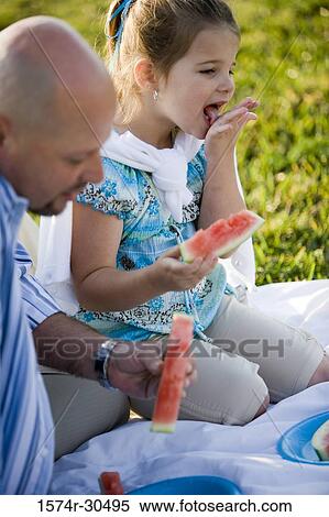 Stock Photography - Father and daughter eating watermelon. Fotosearch