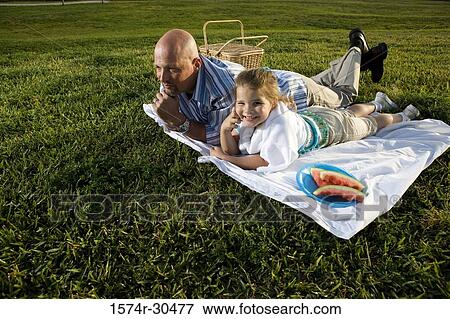 Stock Photo - Father and daughter lying on a blanket and smiling. Fotosearch