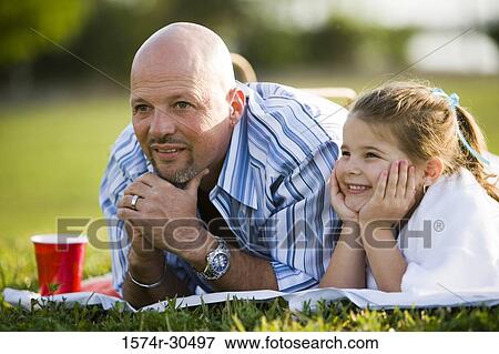 Stock Photo - Father and daughter lying side by side and smiling. Fotosearch