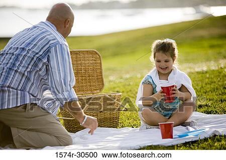 Stock Image - Father and daughter on a picnic at a park. Fotosearch