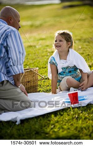 Stock Image - Father and daughter on a picnic at a park. Fotosearch