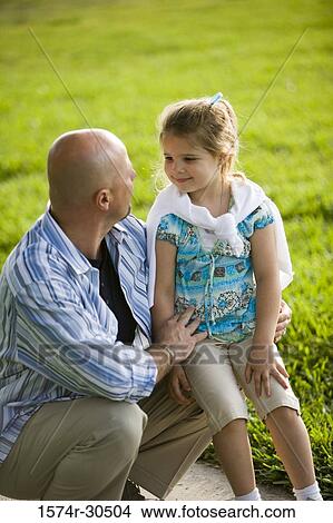 Father and daughter sitting on a pathway in a park View Large Photo Image Picture - Father and daughter sitting on a pathway in a park. Fotosearch