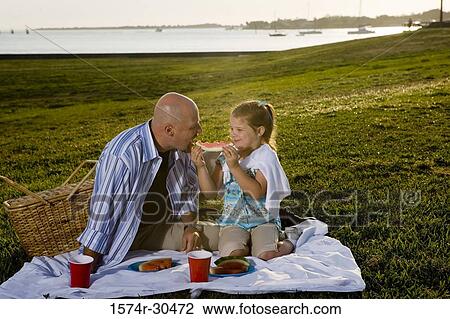 Father and daughter sitting on a blanket and eating watermelon View Large Photo Image Stock Image - Father and daughter sitting on a blanket and eating watermelon. Fotosearch