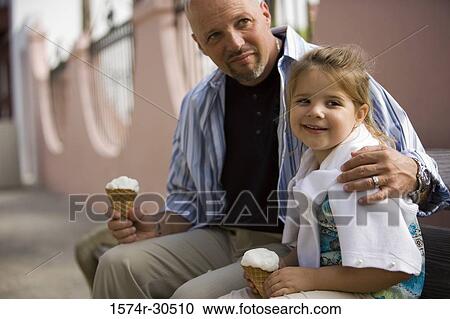 Stock Image - Father and daughter sitting together and holding ice cream cone. Fotosearch