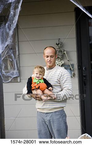 Father holding her son in front of a house View Large Photo Image Stock Image - Father holding her son in front of a house. Fotosearch