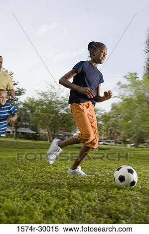 Stock Photography - Father playing soccer ball with their children at park. Fotosearch