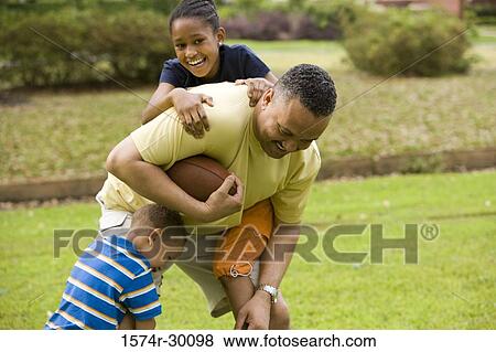 Stock Photo - Father playing with their children at park. Fotosearch