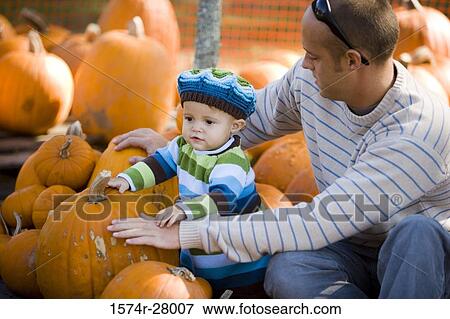 Father with his son amid pumpkins View Large Photo Image Stock Photo - Father with his son amid pumpkins. Fotosearch