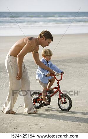 Father with his son riding a bicycle at the beach View Large Photo Image Picture - Father with his son riding a bicycle at the beach. Fotosearch