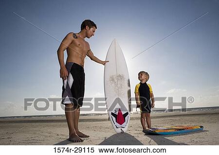 Father with his son standing by surfboard at the beach View Large Photo Image Stock Photography - Father with his son standing by surfboard at the beach. Fotosearch