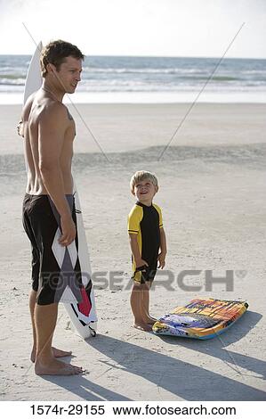 Father with his son standing by surfboard at the beach View Large Photo Image Stock Photography - Father with his son standing by surfboard at the beach. Fotosearch