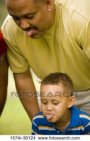 Father with his son sticking out tongue and making a face at park View Large Photo Image Picture - Father with his son sticking out tongue and making a face at park. Fotosearch