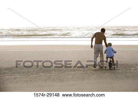 Father with son riding cycle at the beach View Large Photo Image Stock Photo - Father with son riding cycle at the beach. Fotosearch