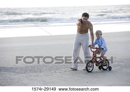 Father with son riding cycle at the beach View Large Photo Image Stock Photo - Father with son riding cycle at the beach. Fotosearch