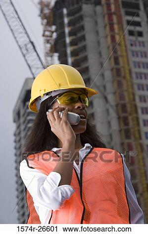 Female architect communicating on mobile phone in front of a building under construction View Large Photo Image Stock Image - Female architect communicating on mobile phone in front of a building under construction. Fotosearch