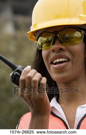 Stock Photography - Female architect wearing hardhat and communicating over walkie-talkie. Fotosearch