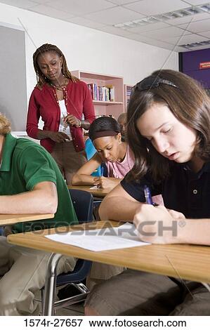 Stock Photo - Female teacher supervising during exam in the classroom. Fotosearch