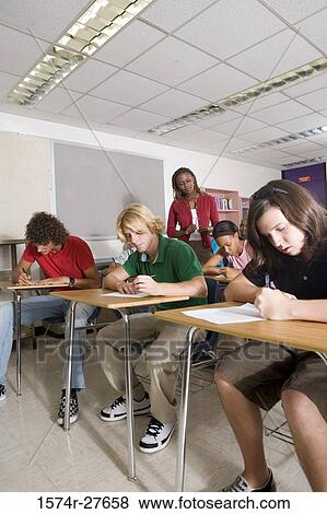 Female teacher supervising during exam in the classroom View Large Photo Image Stock Photo - Female teacher supervising during exam in the classroom. Fotosearch