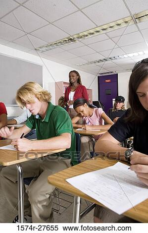 Female teacher supervising during exam in the classroom View Large Photo Image Stock Photography - Female teacher supervising during exam in the classroom. Fotosearch