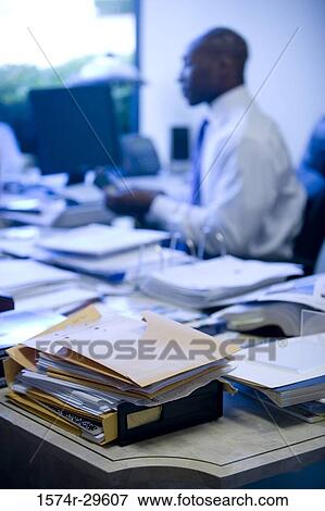 Files kept on table while man working in an office View Large Photo Image Stock Photo - Files kept on table while man working in an office. Fotosearch