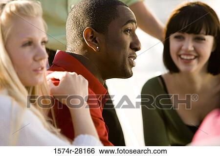 Friends discussing with each other and smiling View Large Photo Image Stock Photograph - Friends discussing with each other and smiling. Fotosearch