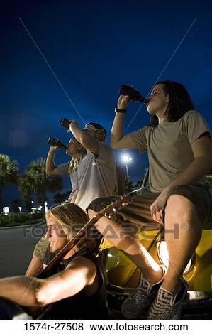 Friends drinking by a car at the parking area View Large Photo Image Stock Photo - Friends drinking by a car at the parking area. Fotosearch