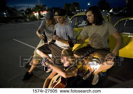 Stock Photography - Friends drinking by a car at the parking area. Fotosearch