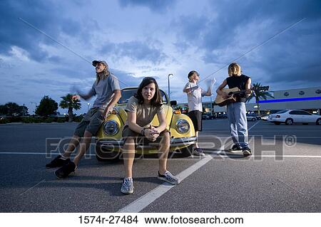 Friends enjoying music by a car at the parking area View Large Photo Image Picture - Friends enjoying music by a car at the parking area. Fotosearch