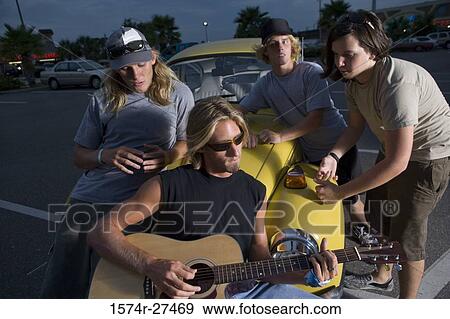 Friends enjoying music by a car at the parking area View Large Photo Image Stock Photo - Friends enjoying music by a car at the parking area. Fotosearch