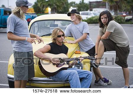 Friends enjoying music by a car at the parking area View Large Photo Image Stock Photo - Friends enjoying music by a car at the parking area. Fotosearch