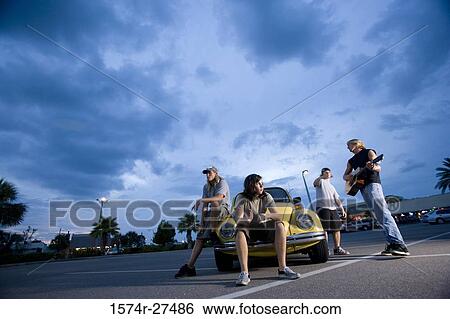 Friends enjoying music by a car at the parking area View Large Photo Image Stock Photograph - Friends enjoying music by a car at the parking area. Fotosearch