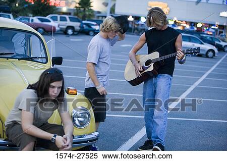 Friends enjoying music by a car at the parking area View Large Photo Image Stock Photography - Friends enjoying music by a car at the parking area. Fotosearch