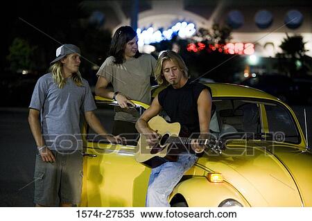 Friends enjoying music by a car at the parking area View Large Photo Image Stock Photography - Friends enjoying music by a car at the parking area. Fotosearch