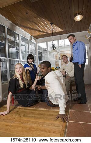 Stock Image - Friends enjoying their drinks in dining room. Fotosearch