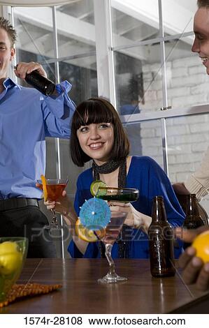 Friends enjoying their drinks in dining room View Large Photo Image Stock Photo - Friends enjoying their drinks in dining room. Fotosearch