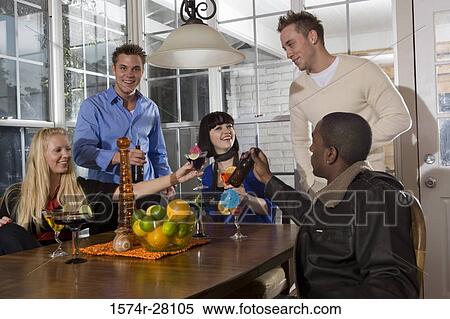 Friends enjoying their drinks in dining room View Large Photo Image Stock Photography - Friends enjoying their drinks in dining room. Fotosearch