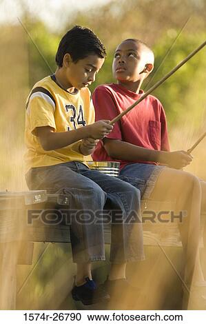 Friends fishing with fishing rods sitting on the jetty View Large Photo Image Stock Image - Friends fishing with fishing rods sitting on the jetty. Fotosearch