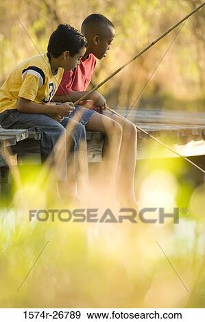 Friends fishing with fishing rods sitting on the jetty View Large Photo Image Stock Photo - Friends fishing with fishing rods sitting on the jetty. Fotosearch