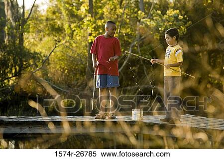 Friends fishing with fishing rods while standing on the jetty View Large Photo Image Stock Photography - Friends fishing with fishing rods while standing on the jetty. Fotosearch