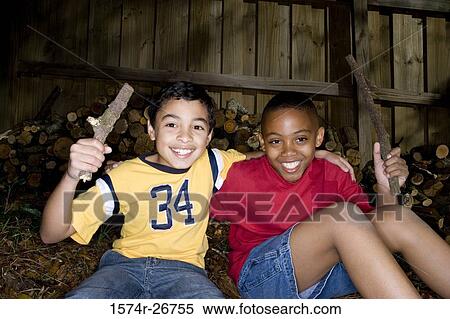 Friends holding sticks and sitting by logs View Large Photo Image Stock Photography - Friends holding sticks and sitting by logs. Fotosearch
