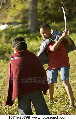 Stock Photo - Friends playing with a sword and stick at forest. Fotosearch
