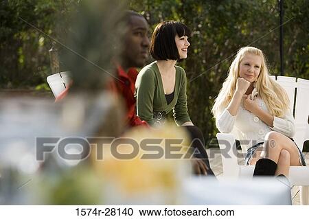 Friends sitting on armchairs and smiling View Large Photo Image Stock Image - Friends sitting on armchairs and smiling. Fotosearch