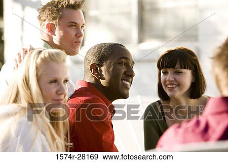 Stock Photo - Friends sitting on armchairs and smiling. Fotosearch