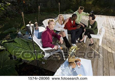 Friends sitting on armchairs on wooden deck View Large Photo Image Stock Photograph - Friends sitting on armchairs on wooden deck. Fotosearch