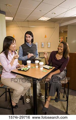 Stock Photograph - Friends sitting together and eating food. Fotosearch